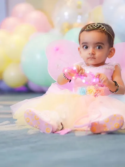 Dressed as a little fairy, this baby girl looks right at the camera. Themed photoshoots allow us to capture a sense of wonder and play, complete with wings and a tiara.