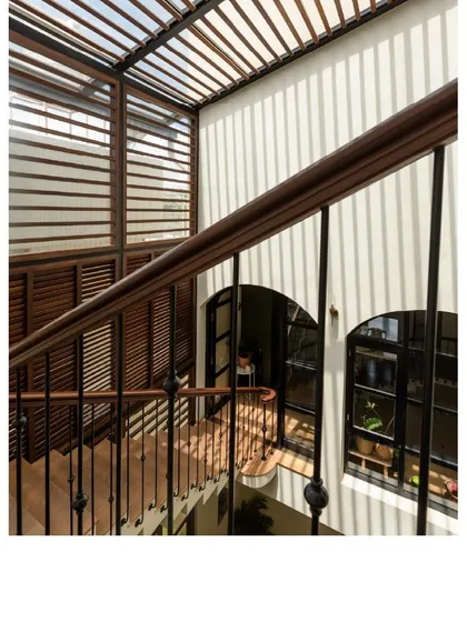 Light and shadow play on the walls of this staircase. The slatted roof and open design allow sunlight to filter through, creating dynamic patterns that change throughout the day.