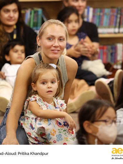 A parent and child enjoy the storytelling session together in our elementary library. We encourage family participation in our literacy events to build a strong community of readers.