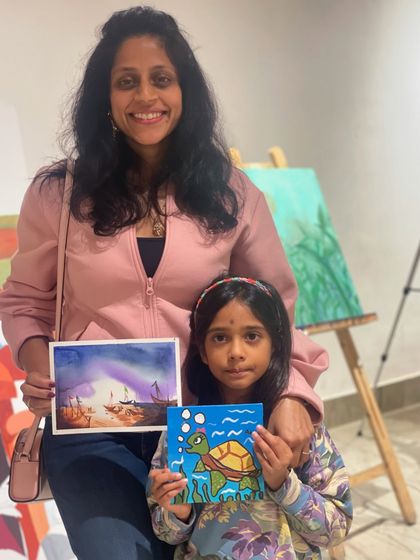 A mother and daughter duo with their lovely paintings. The daughter created a cute turtle, while the mom painted a dreamy seascape.