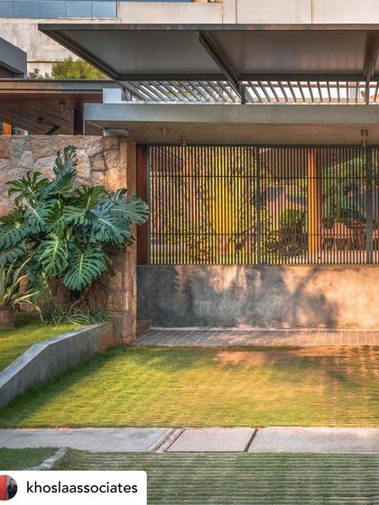 A view of a serene garden with a water feature and a slatted wooden screen. The interplay of stone, water, and wood against the lush green lawn creates a textured and visually interesting landscape.