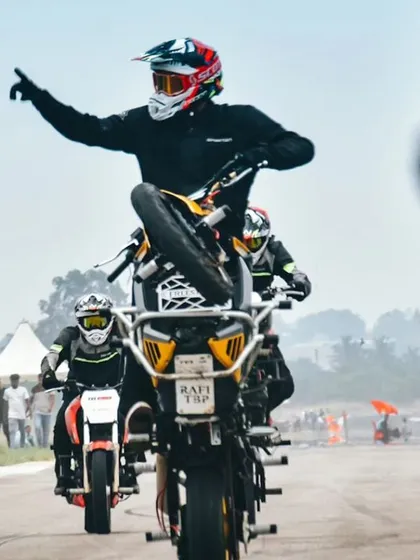 Another shot of the synchronized wheelie, with the lead rider signaling to the crowd. The performers are not just athletes; they are entertainers who know how to work an audience.