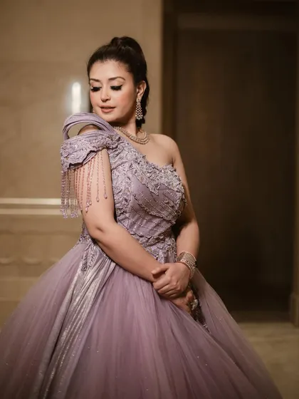 A close-up of our royal lavender glitter ball gown. The one-shoulder design features intricate silver embroidery and stunning beaded tassels that add movement and glamour.