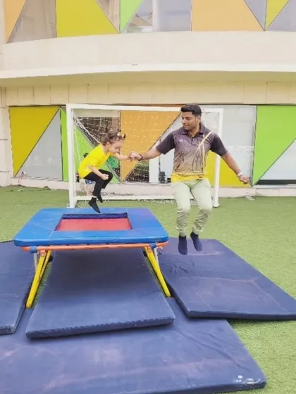 An instructor and a student jump together on the trampoline, showcasing the fun and interactive nature of our summer camp fitness activities. We believe in learning and growing together through shared experiences.