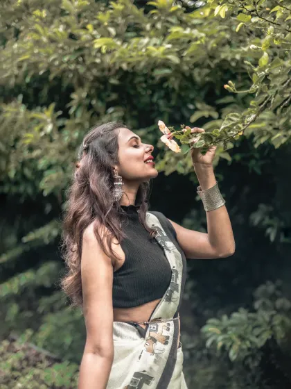 A sensory portrait of a woman in a saree, gently smelling a flower. This shot combines natural beauty with the elegance of ethnic wear.