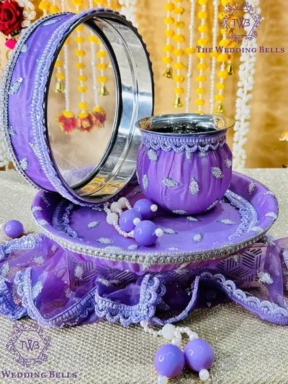 For those who love a bit of glam, this purple Karvachauth thali set is perfect. The fabric has a subtle shimmer, and the entire set is coordinated with matching beaded hangings for a complete, luxurious look.