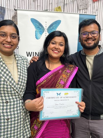 A winner poses with her certificate, supported by friends and family. Our community is a supportive one.