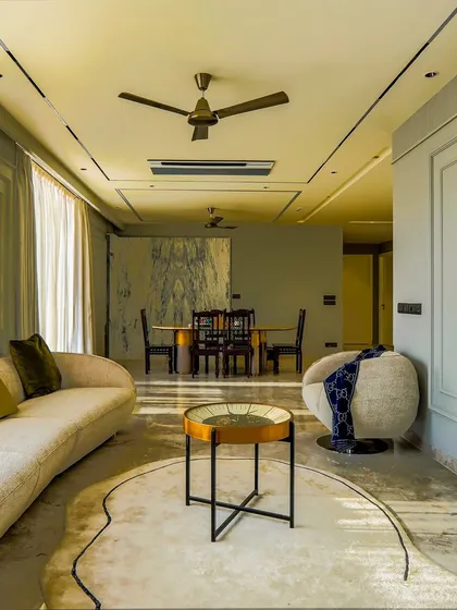 Another view of the drawing room, showing the seamless flow into the dining area. The consistent neutral palette and use of natural light create a cohesive and airy open-plan living space.