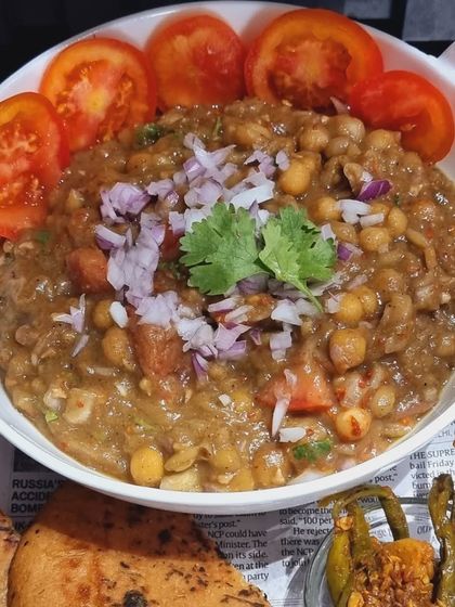 A full bowl of my homemade Matra, garnished with fresh tomatoes, onions, and coriander. It's a wholesome and tangy chickpea curry that is both light and satisfying.
