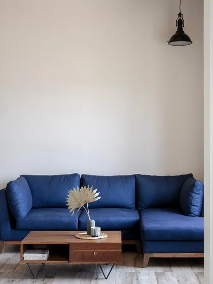A cozy lounge area with a deep blue sofa and a simple wooden coffee table. The minimalist decor ensures that the focus remains on comfort and relaxation.