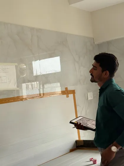 On-site, comparing the digital plan on my tablet to the actual wall where a marble-finish panel is being installed.