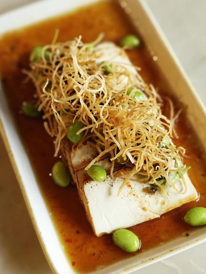 A top-down view of the Tofu Carpaccio, showcasing the delicate arrangement of seared tofu, edamame, and crispy sweet potato.