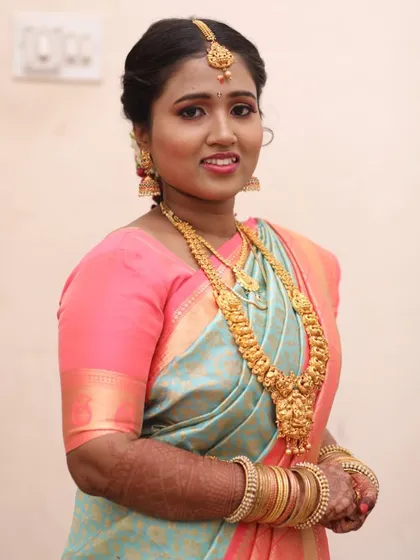 Another angle of this beautiful Muhurtham look, showing how the makeup enhances her smile. The gold jewelry and pastel Kanjivaram saree are perfectly coordinated for a timeless appearance.