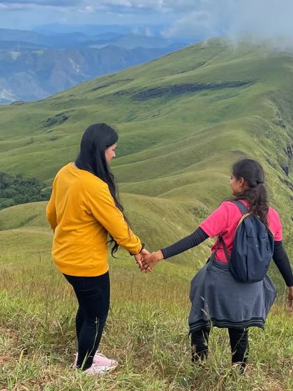 Two friends holding hands and walking towards the stunning vista at Nethravathi peak, a perfect picture of friendship and adventure.