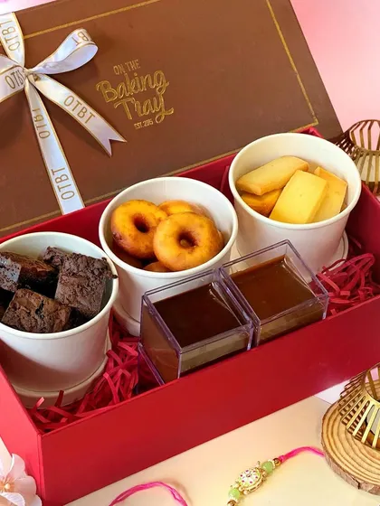 The Dunk'In Hamper was a fun and interactive gift for Rakhi. It came with mini doughnuts, brownie bites, and vanilla cookie sticks, complete with separate dips of milk chocolate and dark chocolate for a shared dessert experience.