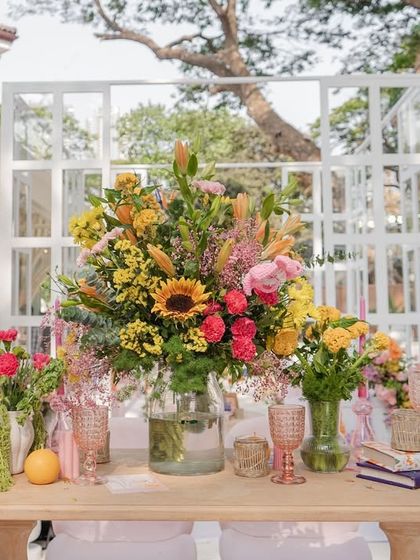 A stunning, large-scale floral arrangement on a console table, acting as a major decorative feature with its mix of sunflowers, roses, and other colorful blooms.