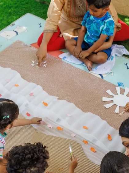 Children work together on a large-scale art project, creating a beach scene. Collaborative art teaches teamwork and communication, as they negotiate space and share materials to achieve a common goal.