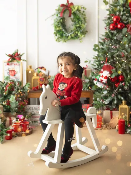 A classic childhood moment on a rocking horse, set against a backdrop of twinkling Christmas lights. These are the memories that make the holidays special.