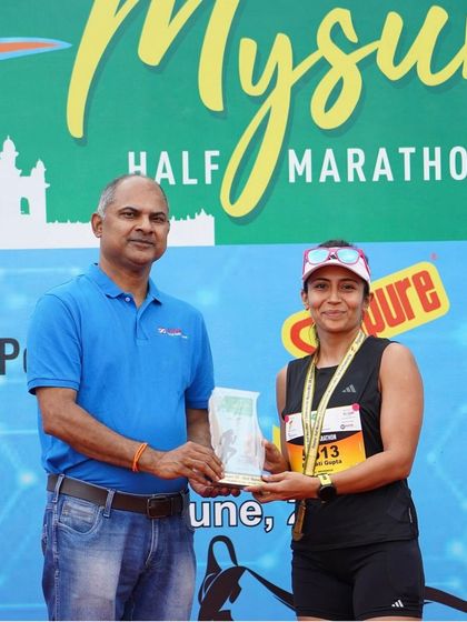 Receiving my trophy at the Mysuru Half Marathon. It's an honor to be recognized on the podium, and it fuels my passion to help other runners achieve their own moments of success.