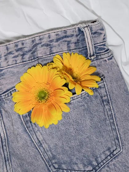 A creative flat-lay of the same jeans with yellow flowers in the pocket. This adds a touch of lifestyle and personality to a standard product photo.