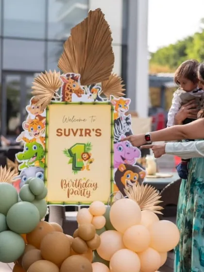 A candid moment as the family arrives at Suvir's jungle-themed first birthday party. The personalized welcome sign with cute safari animals is the perfect start to the celebration.