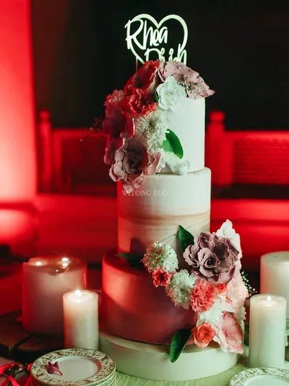 A sweet ending to a beautiful day. This multi-tiered wedding cake, adorned with delicate sugar flowers, was surrounded by candles, creating a romantic focal point for the reception.