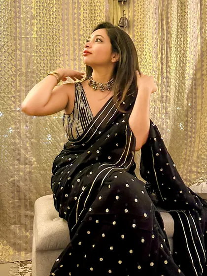 A candid-style shot, capturing the festive mood. The combination of the black saree, silver jewelry, and red lipstick is a classic for a reason.