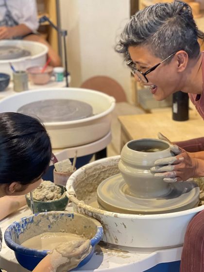 A moment of joy and connection as I share a laugh with a student over a freshly thrown pot.