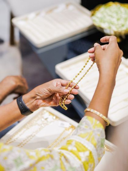 A guest at our Hyderabad event carefully inspects a delicate gold chain, appreciating the craftsmanship and detail of the piece.