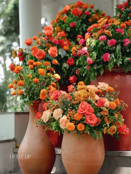 Terracotta vases of varying sizes filled with arrangements of orange roses and marigolds. This rustic and traditional floral display added warmth and color to the Haldi ceremony in Rishikesh.