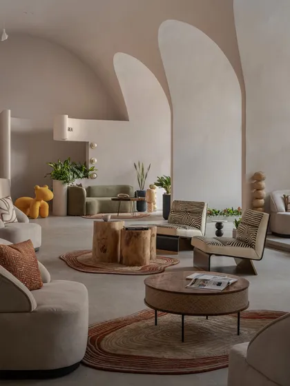 Another perspective of the main lounge area, highlighting the mix of textures from handcrafted wooden stools, plush sofas, and patterned rugs, all under the gentle curve of the vaulted ceiling.