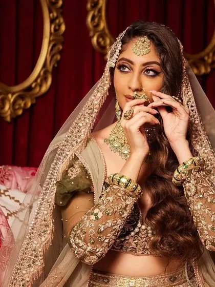 This modern bridal look features soft, romantic waves and a stunning lehenga. The makeup is glamorous yet understated, allowing the bride's natural beauty and the intricate outfit to take center stage.