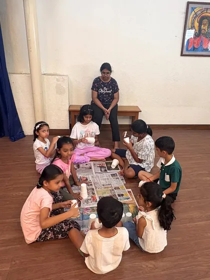 An instructor sits with a group of young girls as they work on their paper cup crafts. We ensure small group sizes so every child gets the attention and guidance they need to succeed.