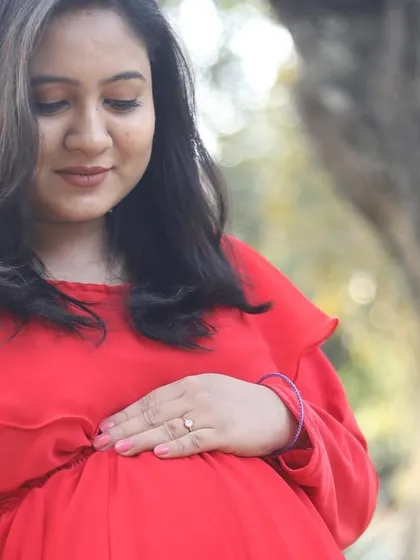 A close-up, gentle moment from the maternity shoot. The makeup is minimal and fresh, focusing on clean skin.