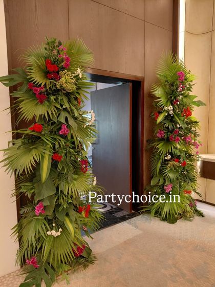 We created these large, lush floral arrangements to flank the entrance to a reception hall. The arrangements are made with tropical leaves and colorful flowers, creating a dramatic and vibrant welcome.