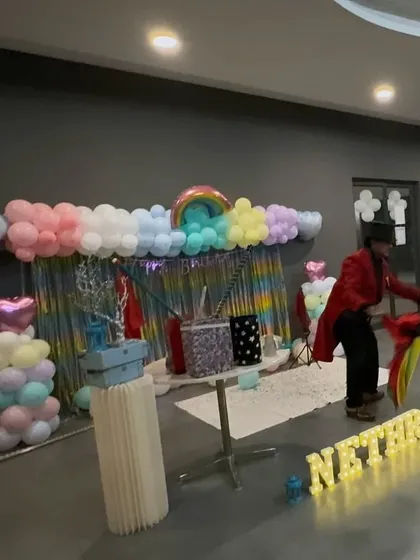 A magician performing at a rainbow-themed birthday party, keeping the kids entertained and amazed.