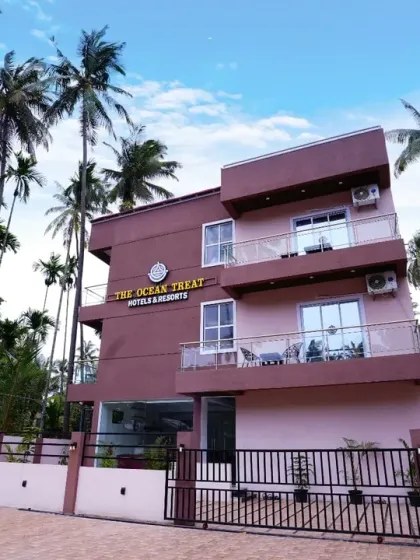 A slightly different angle of the hotel's exterior, showing the entrance gate and parking area. This provides practical information for guests while maintaining an aesthetically pleasing composition.