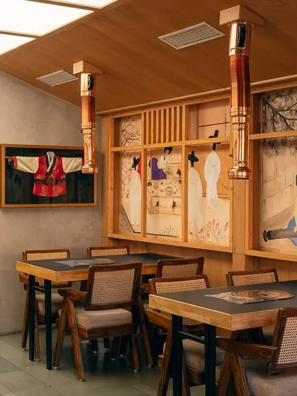 This section of the restaurant features hand-painted murals depicting traditional Korean life. We paired these artistic elements with functional dining tables and custom copper exhausts, ensuring the space is as practical as it is beautiful.