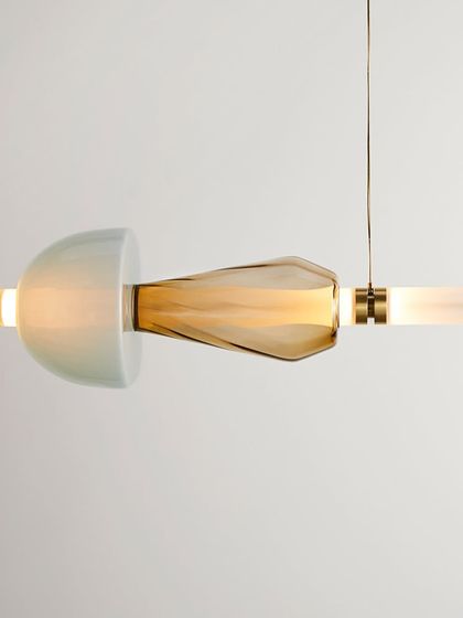 A close-up of a single Luna Kaleido element, showing the combination of a semi-translucent dome and a textured, amber-colored glass piece.