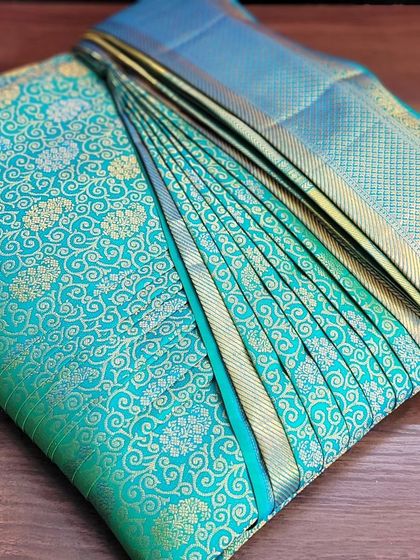 This stunning turquoise bridal saree is folded and ready for a reception. The compact fold makes it easy to pack alongside other wedding outfits.