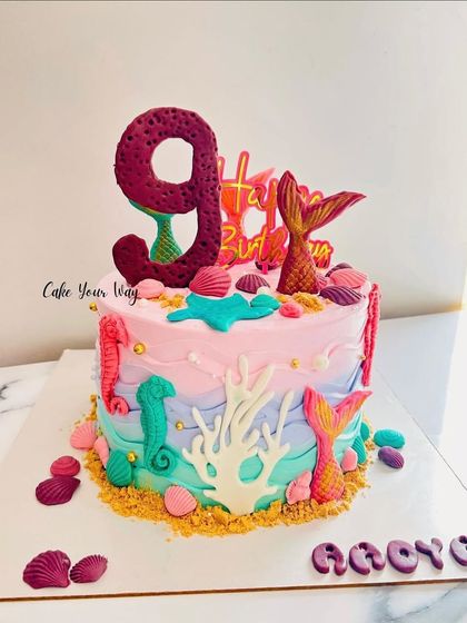 A fin-tastic mermaid cake for a 9th birthday. The ombre frosting and handcrafted sea elements create a beautiful underwater scene.