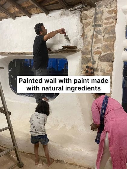 A volunteer painting a wall with natural, chemical-free paint during our community building event. It's a beautiful and healthy alternative to toxic commercial paints.