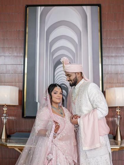 An elegant portrait of the couple in front of a modern art piece, blending their classic attire with contemporary surroundings.