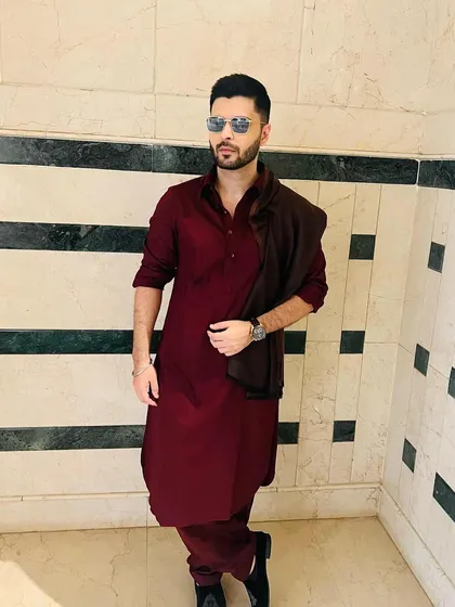 Another shot of the maroon Pathani suit, styled with sunglasses and a shawl. This demonstrates the versatility of the garment, easily dressed up for a sophisticated look.
