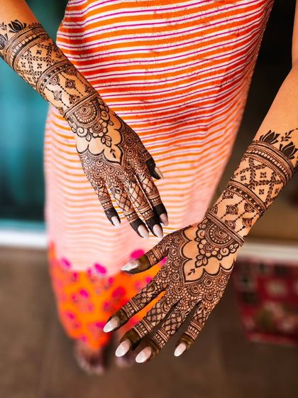 A full view of a lovely engagement henna design, with matching patterns on both arms that extend just past the wrist.