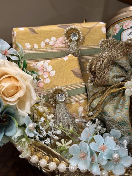 A detail shot showing the beautiful gift wrapping within a hamper, featuring floral paper and pearl-tassel embellishments.