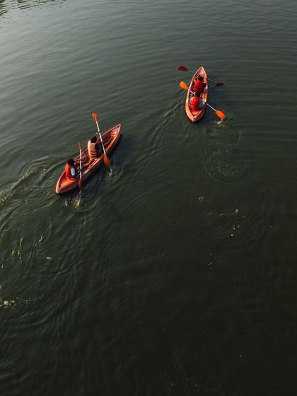 A beautiful top-down view of two kayaks, showcasing the vibrant colors of the boats against the dark water.