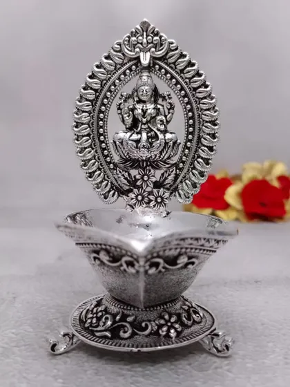 Is antique German silver Lakshmi Diya mein vathi (batti) rakhne ke liye stand bhi hai. Iska design bahut hi traditional hai aur har shubh avsar par roshni karne ke liye perfect hai.