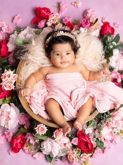 A peaceful baby resting in a bowl of pink flowers. This shot is a beautiful and artistic way to capture the delicate nature of a young baby.