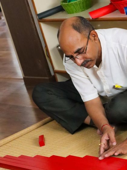An adult learner works with the Red Rods, a core sensorial material. By experiencing the material himself, he gains a deep, personal understanding of how it helps a child to visually discriminate length and prepare for mathematics.